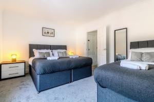 a bedroom with two beds and a mirror at Barnwell by Holmesdale Homes in Kettering