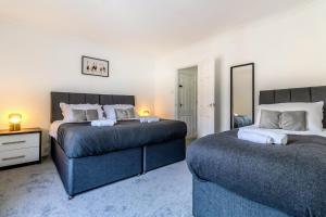 a bedroom with two beds and a mirror at Barnwell by Holmesdale Homes in Kettering