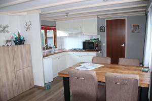 a kitchen with a wooden table and a kitchen with white cabinets at Veluwe Park Reewold Chalet Eclipse in Putten