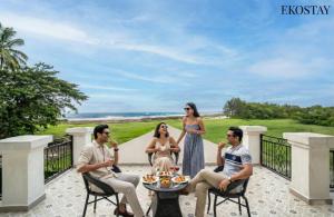 a group of people sitting around a table on a patio at EKOSTAY Luxe - Oceanic Villa in Alibaug