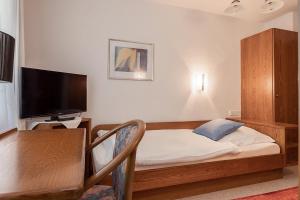 a bedroom with a bed and a desk with a television at Hotel Gästehaus Hirsch in Remseck-Pattonville
