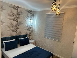 a bedroom with a bed with blue pillows and a window at Firepalace Gabala in Gabala