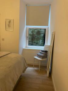 a bedroom with a bed and a window with a chair at Dunoon River Clyde Flat in Innellan