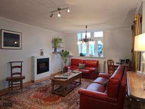 a living room with red furniture and a fireplace at B&B Villa D'Hondt in Blankenberge