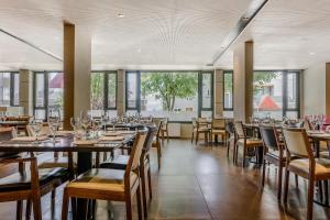 a dining room with tables and chairs and windows at NH Bariloche Edelweiss in San Carlos de Bariloche