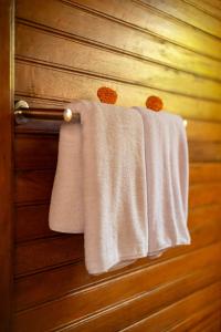 two white towels are hanging on a wooden door at Kubu Diar by Manara in Seraya