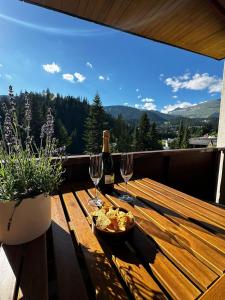 a wooden table with wine glasses and a bowl of food at HappyLaax - Panoramic Penthouse - Pool, Sauna & Private Parking in Laax +55 photos