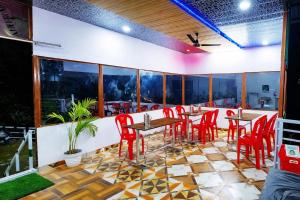 a restaurant with red chairs and tables and windows at shiv shankar resort and hotel in Phata
