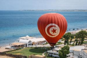 a red hot air balloon flying over a beach at One Resort Aqua Park in Monastir
