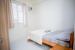 a white bedroom with a bed and a window at Jannish Transient House in Masbate