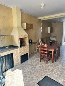 a kitchen with a fireplace and a table and a dining room at Casa Brisa do Mar in Governador Celso Ramos