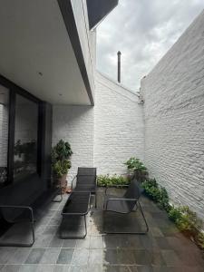 a patio with a couch and chairs next to a brick wall at Maison Bonheur in Bruges