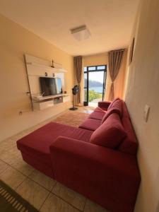 a living room with a red couch and a television at Casa Brisa do Mar in Governador Celso Ramos