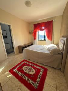 a bedroom with a bed with a red rug on the floor at Casa Brisa do Mar in Governador Celso Ramos