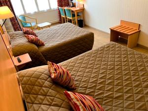 a hotel room with two beds and a table at Hôtel du Cheval Rouge in Versailles