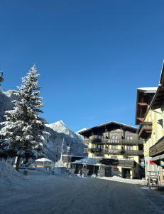 a large building with a tree in the snow at Landhotel Post in Heiligenblut