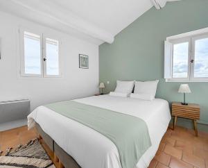 a bedroom with a large white bed with two windows at Maison rénovée avec terrasse et parking privé in Mallemort