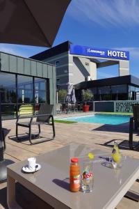 a table with a drink on it next to a hotel at The Originals City, Hôtel Hélios, Roanne Nord in Mably