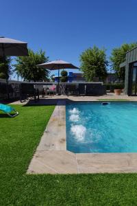 a swimming pool in a yard with grass and umbrellas at The Originals City, Hôtel Hélios, Roanne Nord in Mably