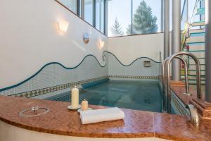 a bathroom with a pool with a sink and a bath tub at Golfhotel Riederhof in Riederalp