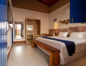 a bedroom with a large bed with a bench in it at Villa Hortensia in Mucugê