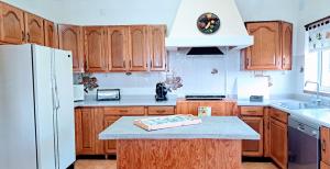 a kitchen with wooden cabinets and a white refrigerator at Casa da Maíssa in Ponta Delgada