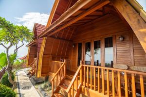 a wooden house with a porch and a balcony at Kubu Diar by Manara in Seraya