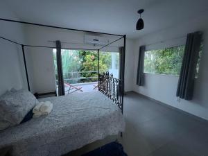a bedroom with a bed and a large glass window at Maison das Artes morere in Cairu