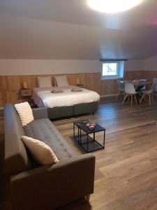 a bedroom with a bed and a couch and a table at B&B Hoeve Terwinghe in Gingelom