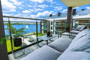 a balcony with a couch and a view of the water at Marina Ostróda - 80 metrów luksusu z widokiem na jezioro in Ostróda
