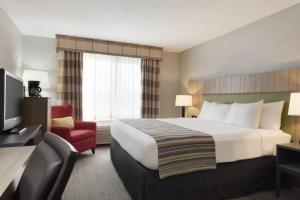 een hotelkamer met een groot bed en een rode stoel bij AmeriVu Inn & Suites - Shakopee in Shakopee