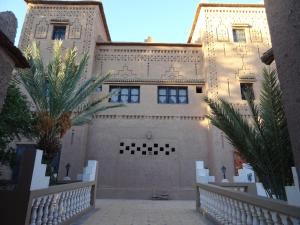 a building with a fence and palm trees in front of it at PALM'SKOURA in Skoura