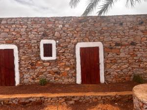 a stone building with two doors and a stone wall at Auberge Nasser in Chinguetti +4 photos