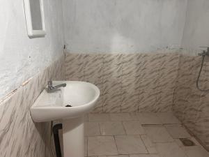 a bathroom with a sink and a tiled floor at Auberge Nasser in Chinguetti