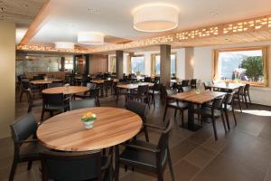 a dining room with wooden tables and chairs at Golfhotel Riederhof in Riederalp