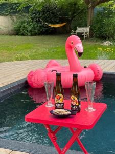 a table with two bottles of beer and a flamingo float at Studio Lumineux avec jardin & piscine à Vaison la Romaine in Vaison-la-Romaine