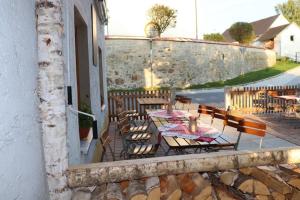 a patio with tables and chairs and a wall at Gasthaus Pension Augenstein in Winzer