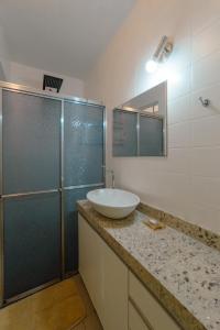a bathroom with a sink and a glass shower at Espaçoso e Confortável Próximo da UEM - EL08 in Maringá