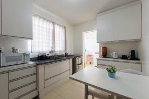 a kitchen with white cabinets and a table in it at Espaçoso e Confortável Próximo da UEM - EL08 in Maringá +29 photos