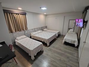 a hospital room with three beds and a mirror at Hotel Avalon Maringá Econômico in Maringá +66 photos