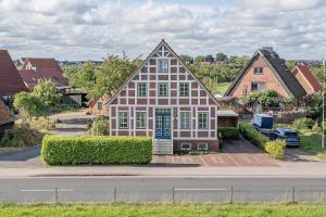 ein großes rot-weißes Haus an einer Straßenseite in der Unterkunft Elbkajüte in Grünendeich
