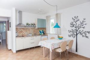 a kitchen with a table and chairs and a kitchen with a tree mural at Apartments Roža in Medulin