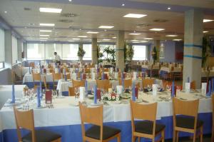 a banquet hall with white tables and chairs and a man at Hotel Alfinden in Puebla de Alfindén