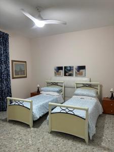 a bedroom with two beds and a ceiling fan at Mary's House in Ciampino