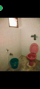 a bathroom with a red toilet and a bucket at pondicherry hostel in Pondicherry