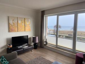 a living room with a television and a large window at Strandhaus Haffkrug in Scharbeutz