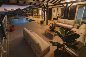 a living room with a couch and a pool at Villa 4 étoiles Le Pic de Malendure in Bouillante