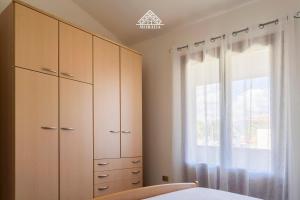 a bedroom with wooden cabinets and a window at Casa Torre di Nora - Morada in Pula +8 photos