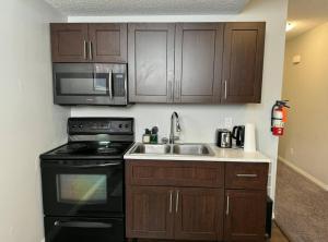 a kitchen with a sink and a stove and microwave at Quiet Comfortable 1-Bedroom in Calgary +8 photos
