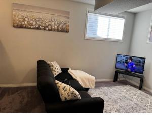 a living room with a couch and a flat screen tv at Quiet Comfortable 1-Bedroom in Calgary